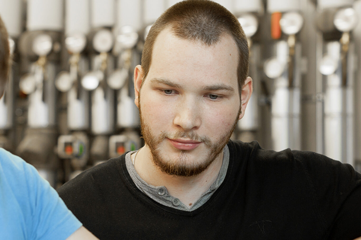 Zwei junge Männer blicken in einer Werkstatt auf ein Werkstück