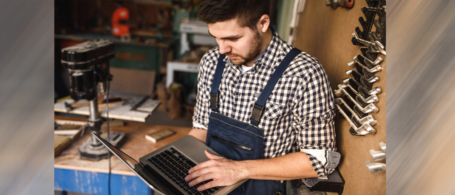 Digitale Bewerbersuche | Tipps für Handwerksbetriebe Junger Mann hält einen Laptop in der Hand, er steht in einer Werkstatt