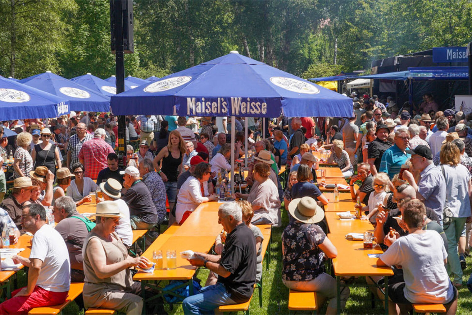 Bratwurstgipfel Park mit Bierbänken und Sonnenschirmen mit vielen Menschen