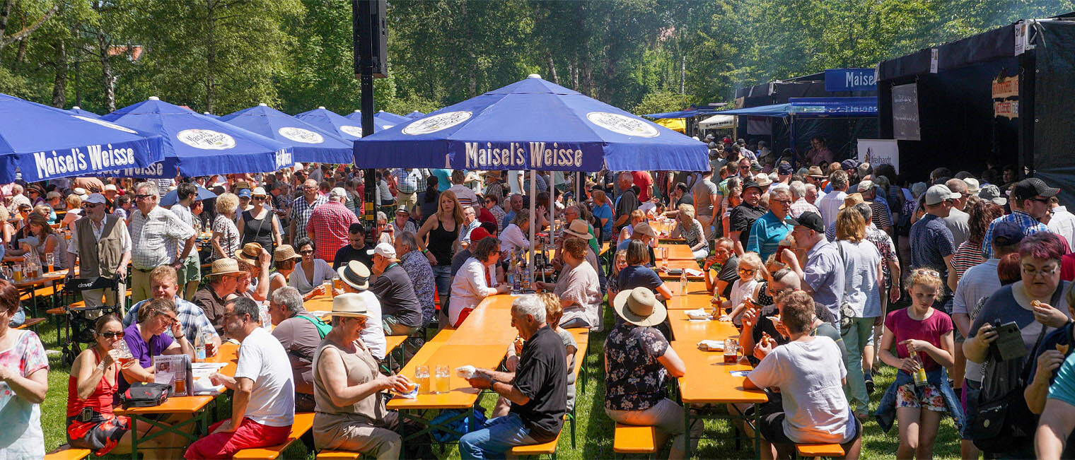 Bratwurstgipfel Park mit Bierbänken und Sonnenschirmen mit vielen Menschen