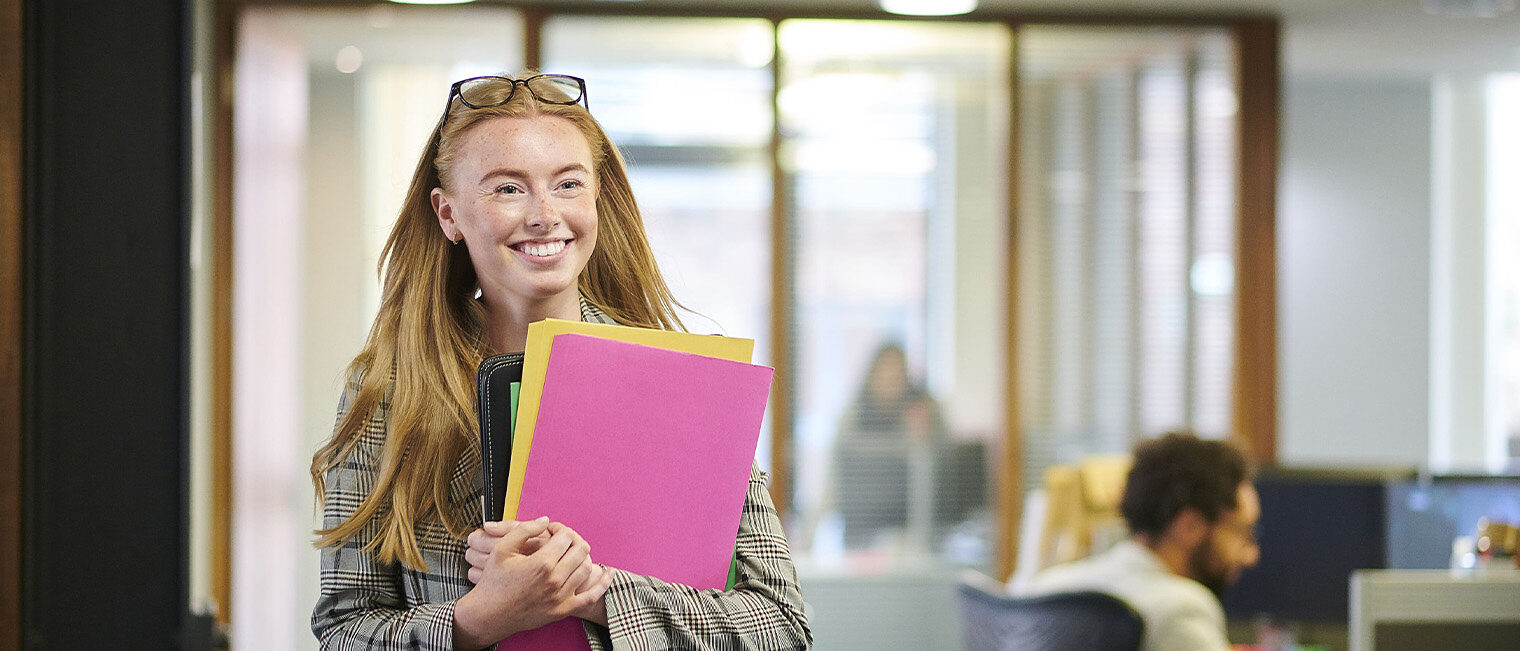 Junge Frau mit Ordnern in der Hand, Symbolfoto für Büropraktikum