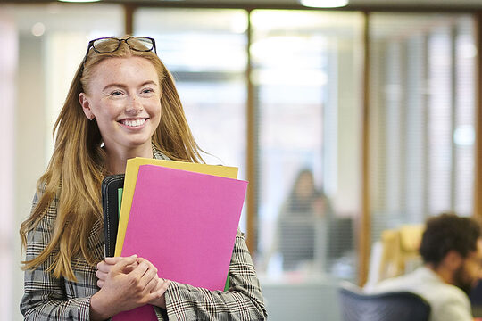 Junge Frau mit Ordnern in der Hand, Symbolfoto für Büropraktikum
