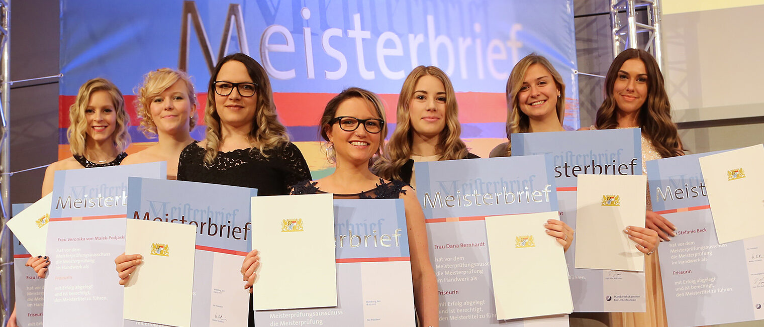 Sieben Meisterinnen im festlichen Outfit mit Meisterbriefen in der Hand, die sich über ihren Abschluss feiern. 