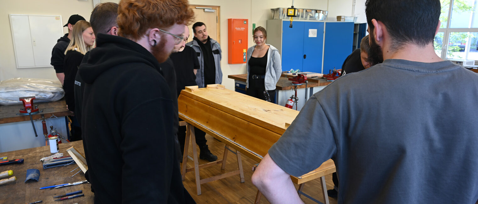 Bestatter Münnerstadt Auszubildende im Bestatterhandwerk stehen um einen Sarg