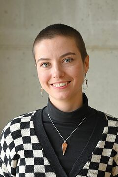 Portrait: Frau mit kurzen Haaren lächelt, trägt SW-karierter Pullover Portrait: Frau mit kurzen Haaren lächelt in die Kamera, Schwarz-Weiß karierter Pullover