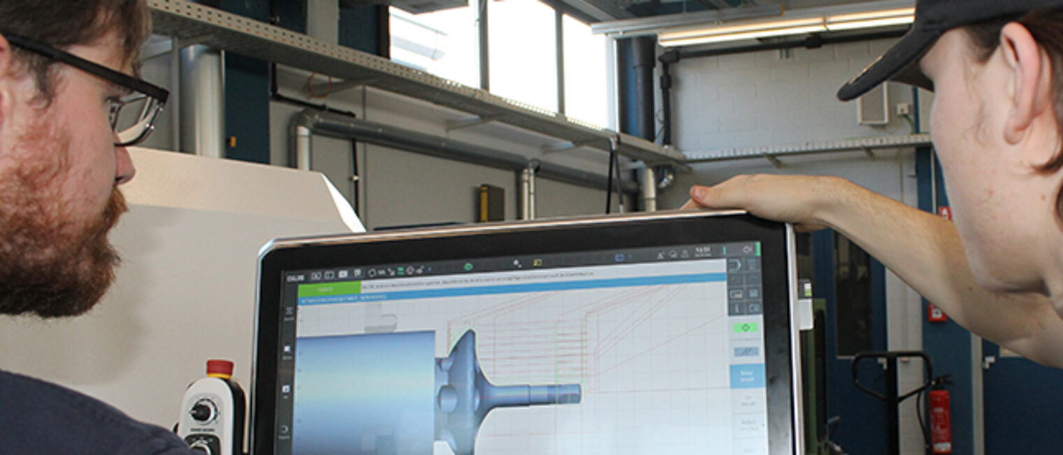 Lehrmeister betreut Schüler beim Bedienen der Drehmaschine in der ÜLU Feinwerkmechanik im Bildungszentrum Aschaffenburg
